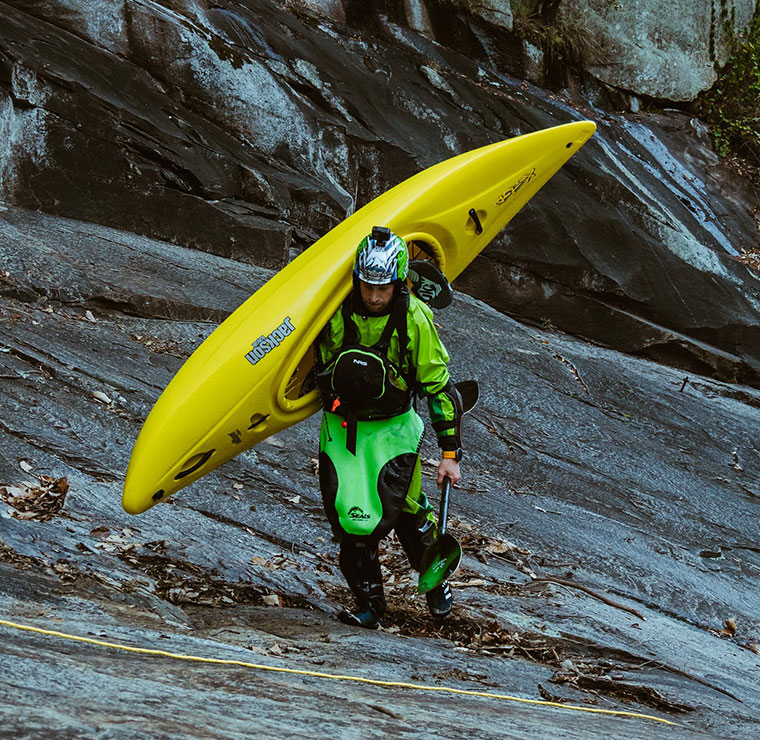 Nick carrying a Jackson Kayak Antix up a rock bank.